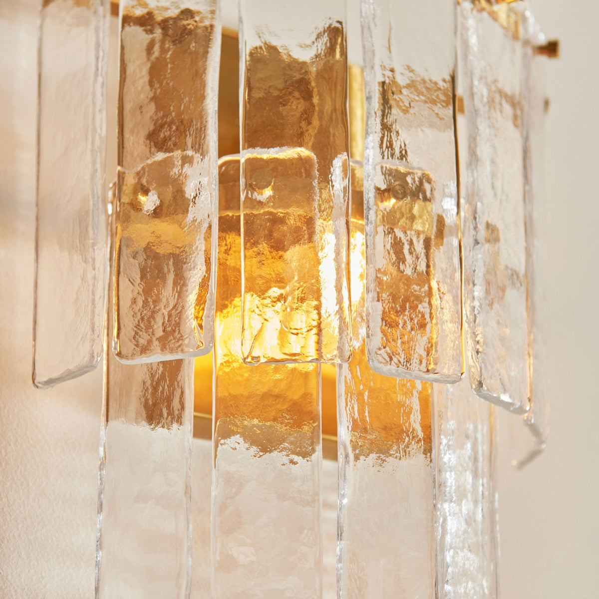A close-up of the sconce, revealing the intricate texture of its glass panels and the warm light within.