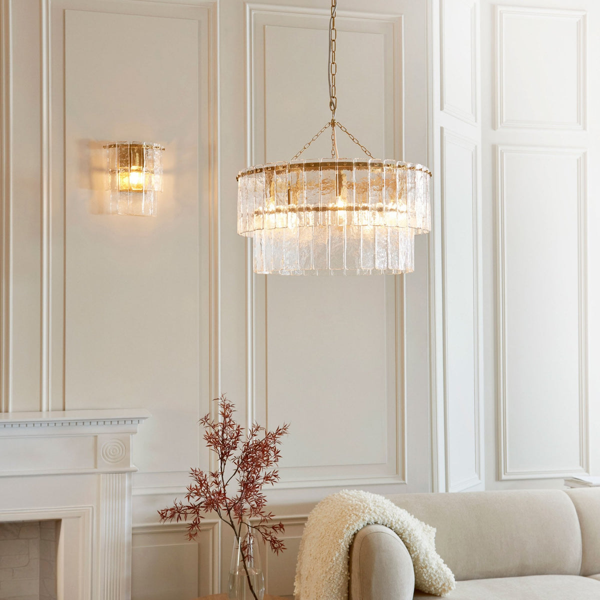 A living room scene featuring a chandelier and a matching sconce, creating a cohesive lighting aesthetic.