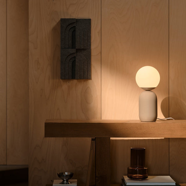 Table lamp with a spherical shade and cylindrical base on a wooden shelf