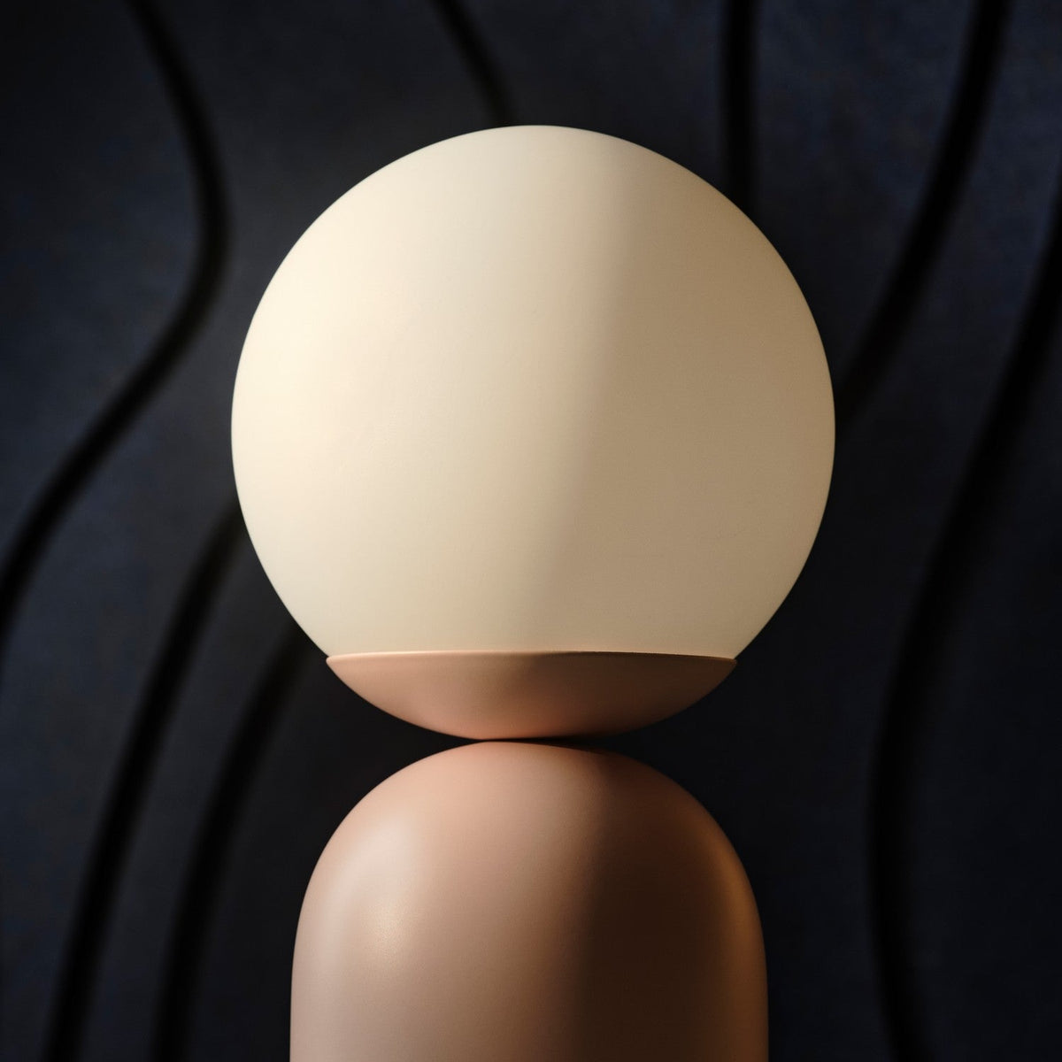 Round cream lamp with a peach base on a dark background