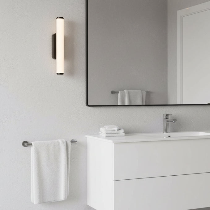 Bathroom with a white vanity, a mirror, a wall-mounted light fixture, and white towels