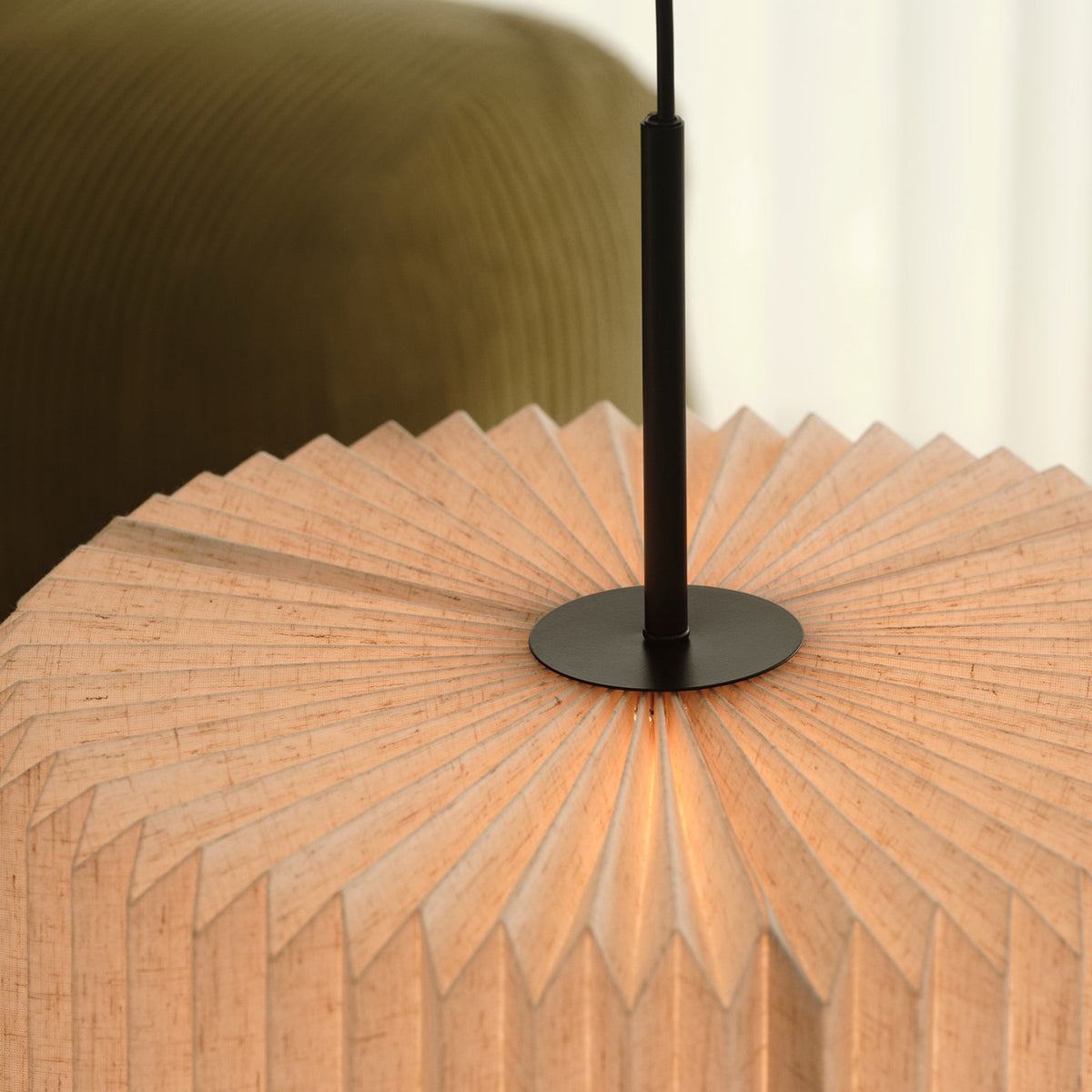 Close up of a pleated fabric lampshade with a black metal stem