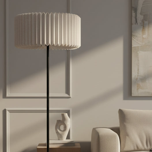 Floor lamp with pleated shade next to a sofa and abstract art