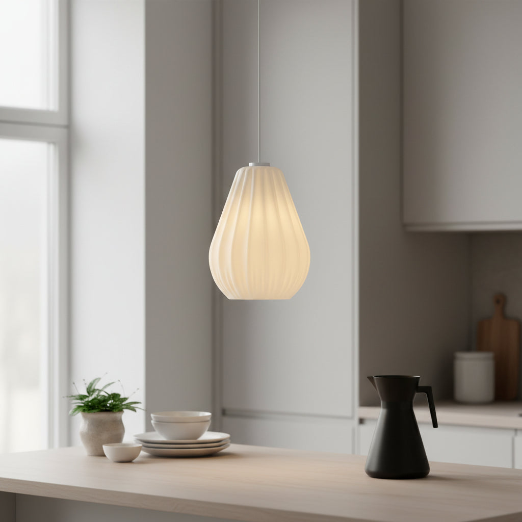 White pleated pendant light hanging above a light wood kitchen counter with dishes and a black coffee pot