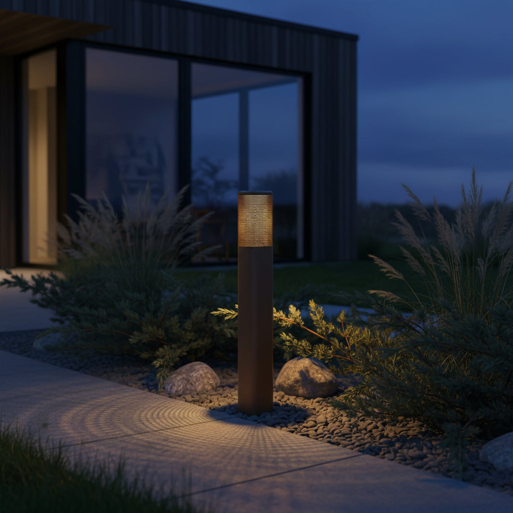 Outdoor bollard light illuminating a pathway next to a modern house at dusk