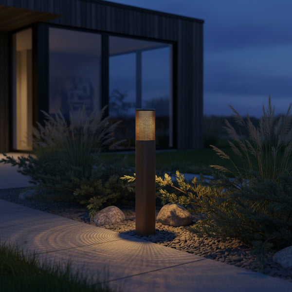 Outdoor bollard light illuminating a pathway next to a modern house at dusk