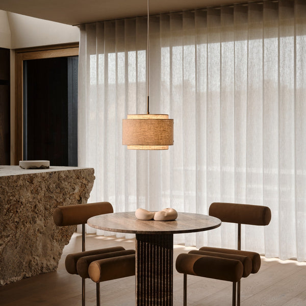 Dining room with a round table, four brown chairs, a pendant light, and sheer white curtains
