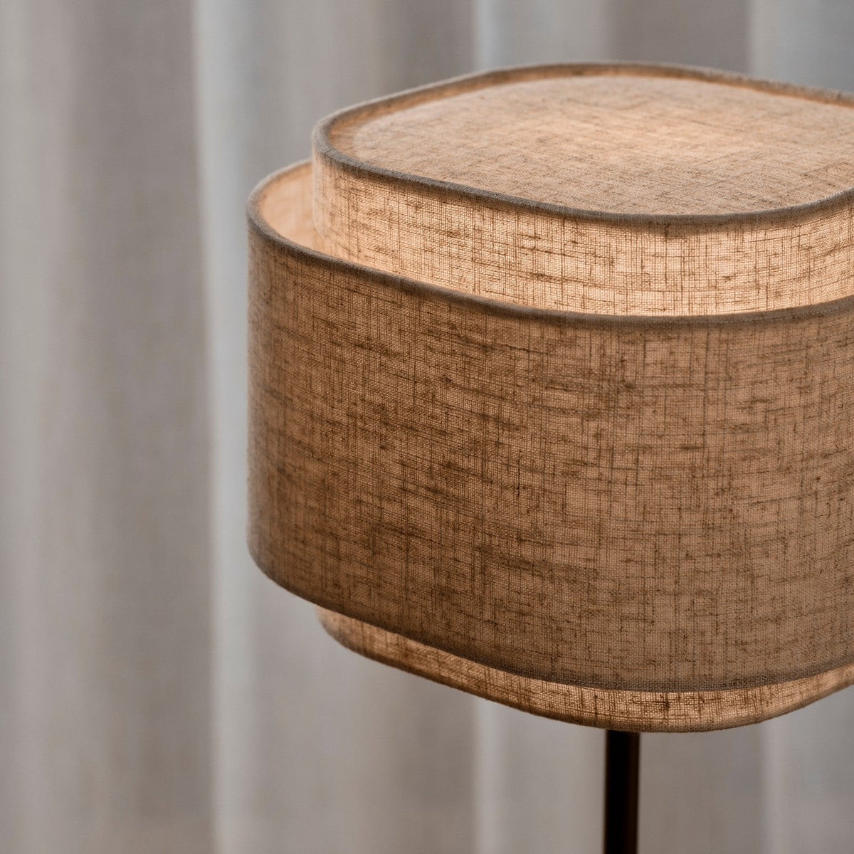 Close up of a two-tiered fabric lampshade with light shining through