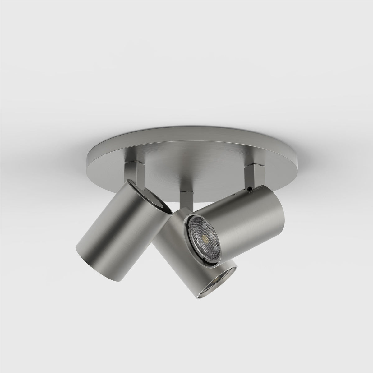 Three brushed nickel cylindrical spotlights attached to a round base on a white ceiling