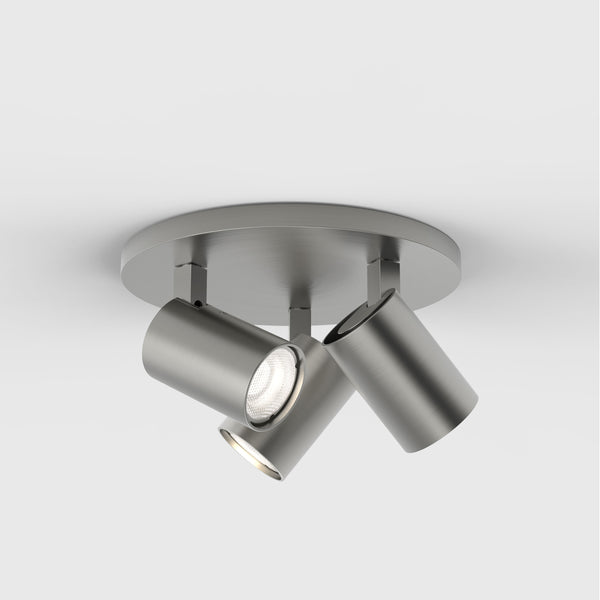 Three brushed metal cylindrical spotlights on a round base, mounted on a white ceiling
