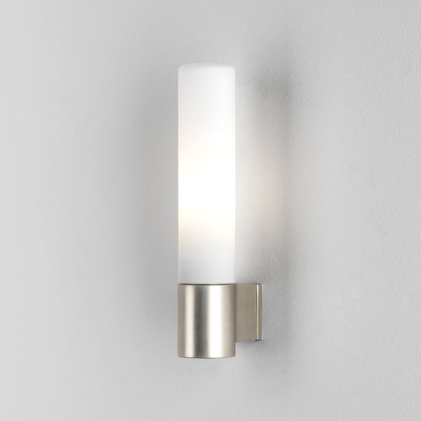 Cylindrical wall light with a brushed metal base and a frosted glass shade, emitting a soft glow