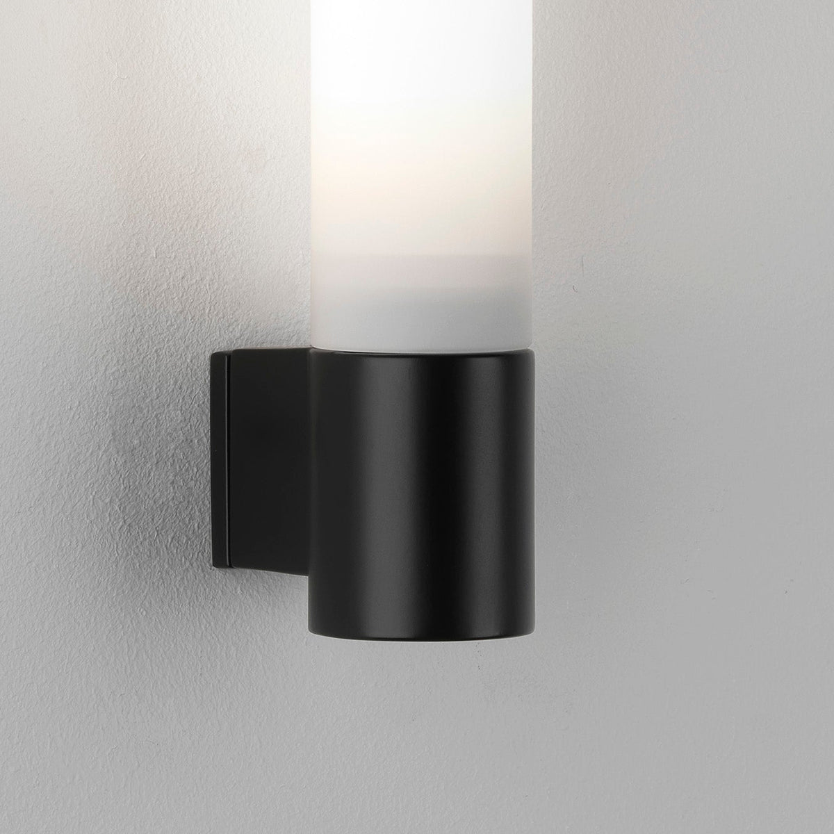 Black cylindrical wall light with a frosted glass shade