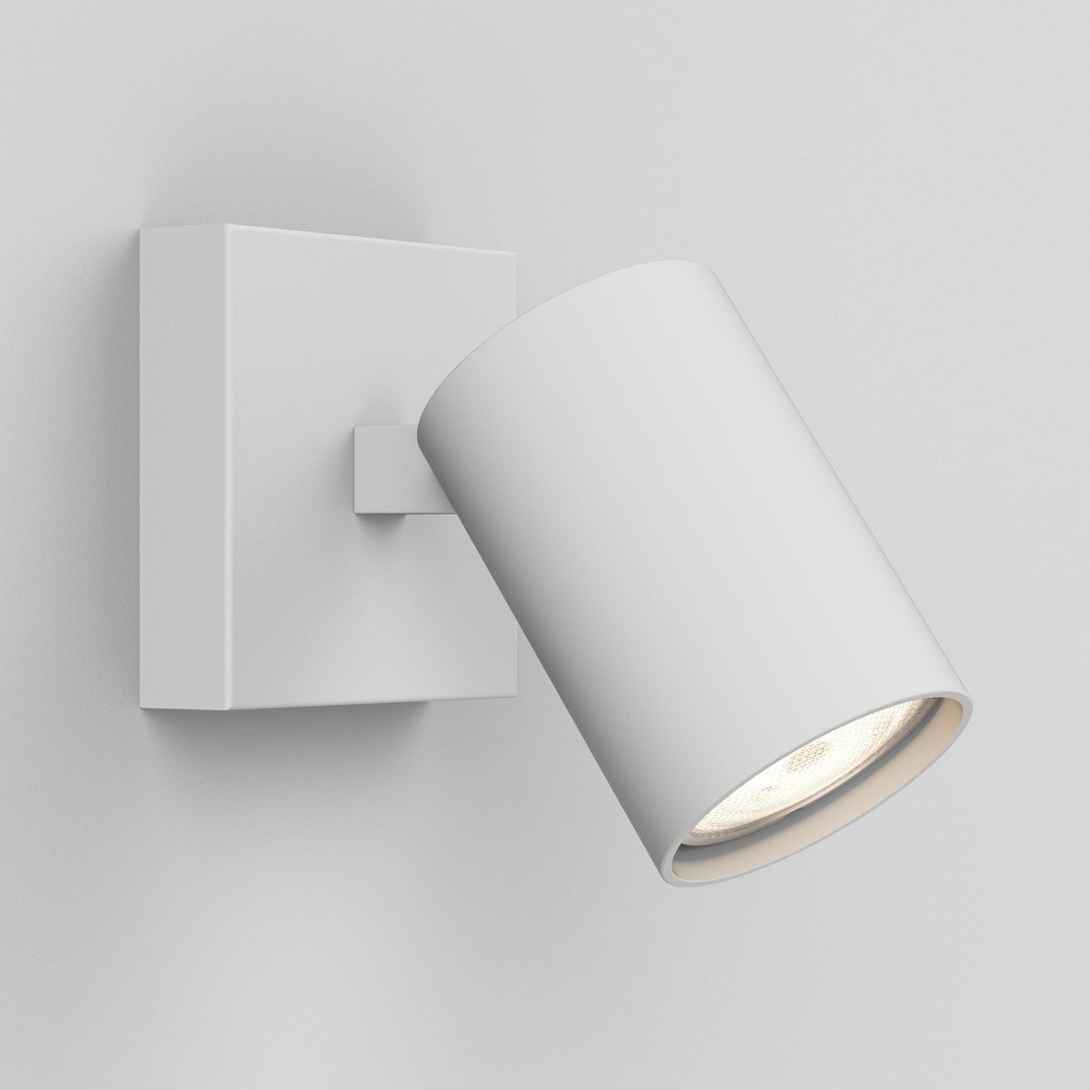 White cylindrical wall light with a square base, angled downwards, emitting a warm glow