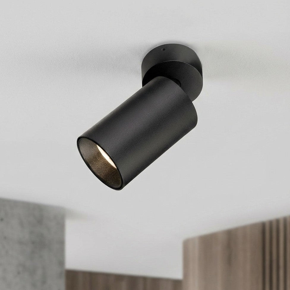 Black cylindrical ceiling spotlight with a warm light