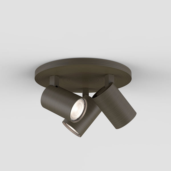 Three dark bronze ceiling spotlights with one light illuminated