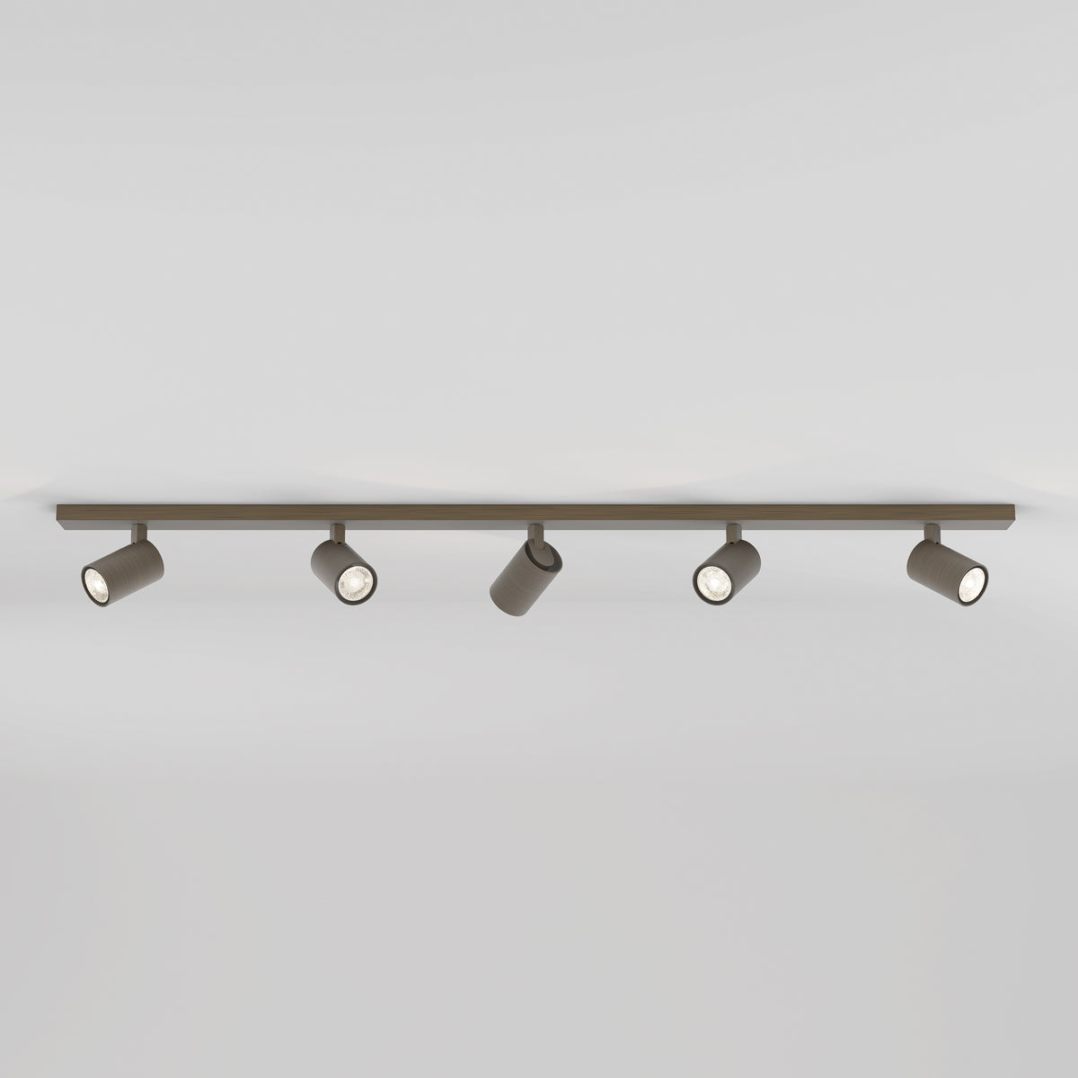 Five brown cylindrical track lights on a brown track against a white ceiling