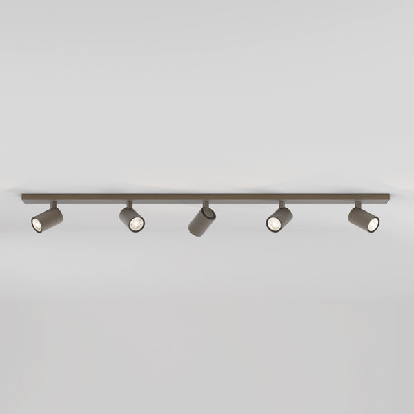 Five brown cylindrical track lights on a brown track against a white ceiling