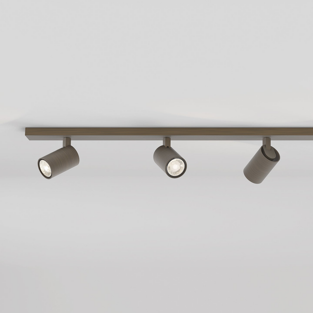 Three cylindrical track lights in a dark finish, two illuminated, on a light-colored ceiling