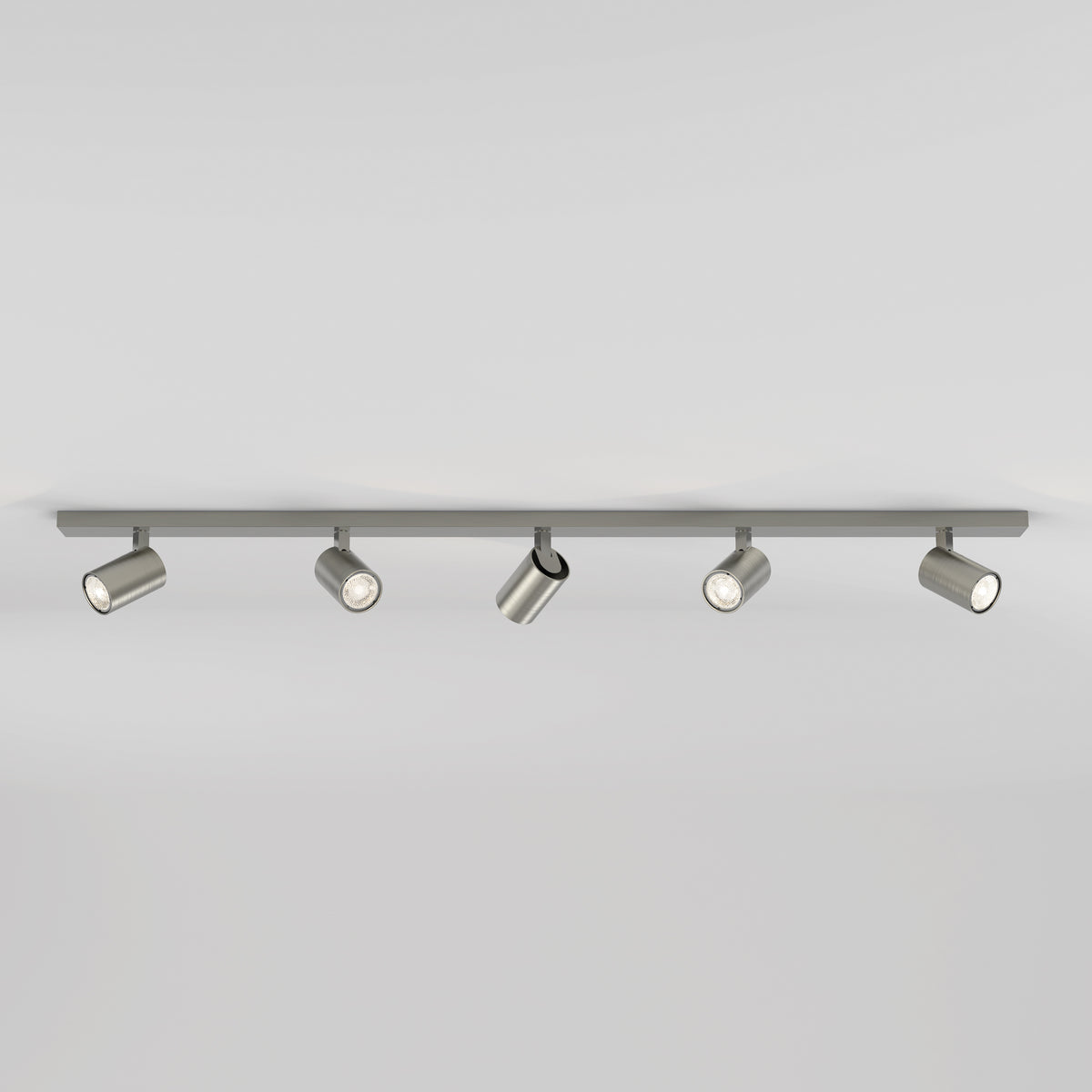 Five brushed metal cylindrical track lights on a grey track against a white ceiling