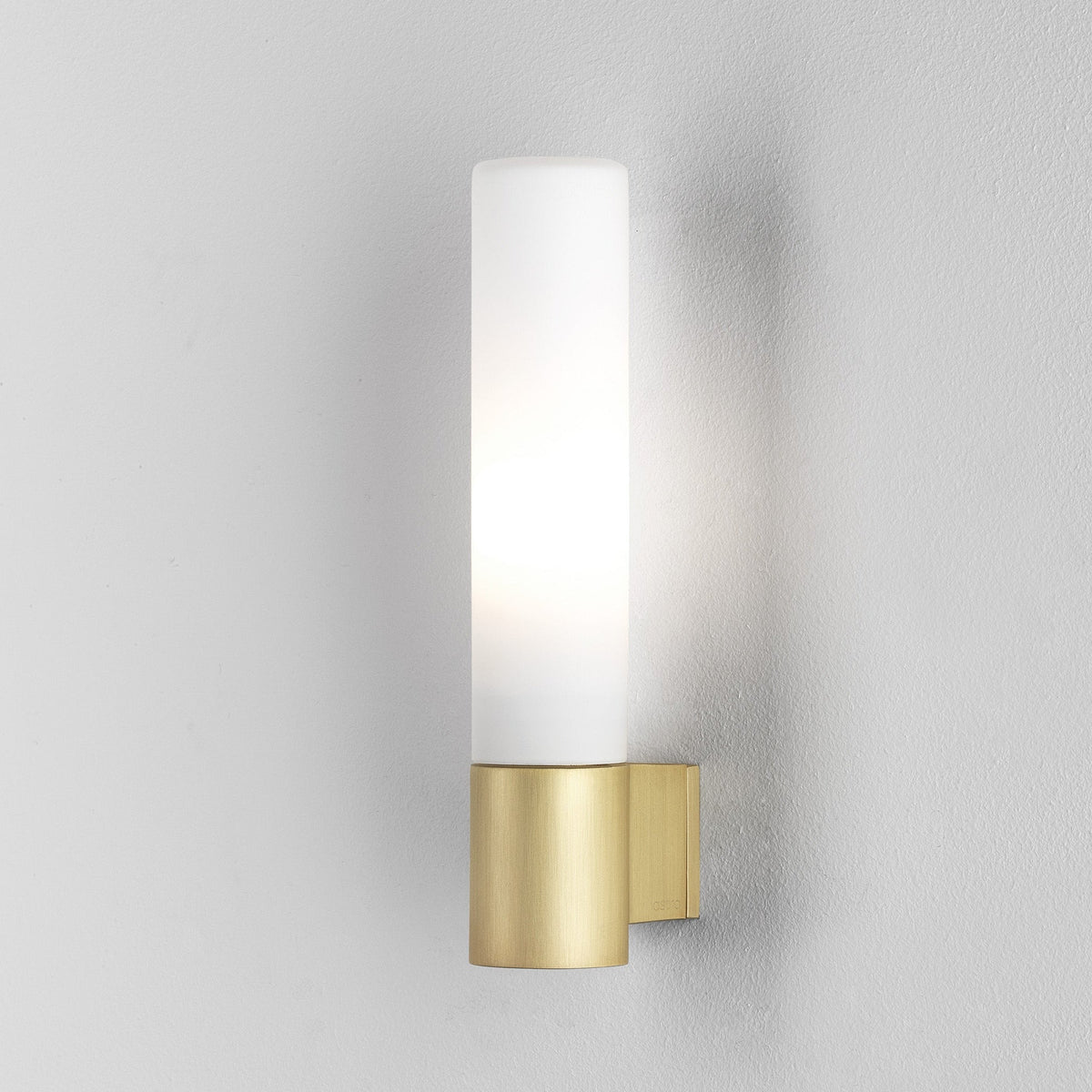 Cylinder-shaped wall light with a brass base and a frosted glass shade