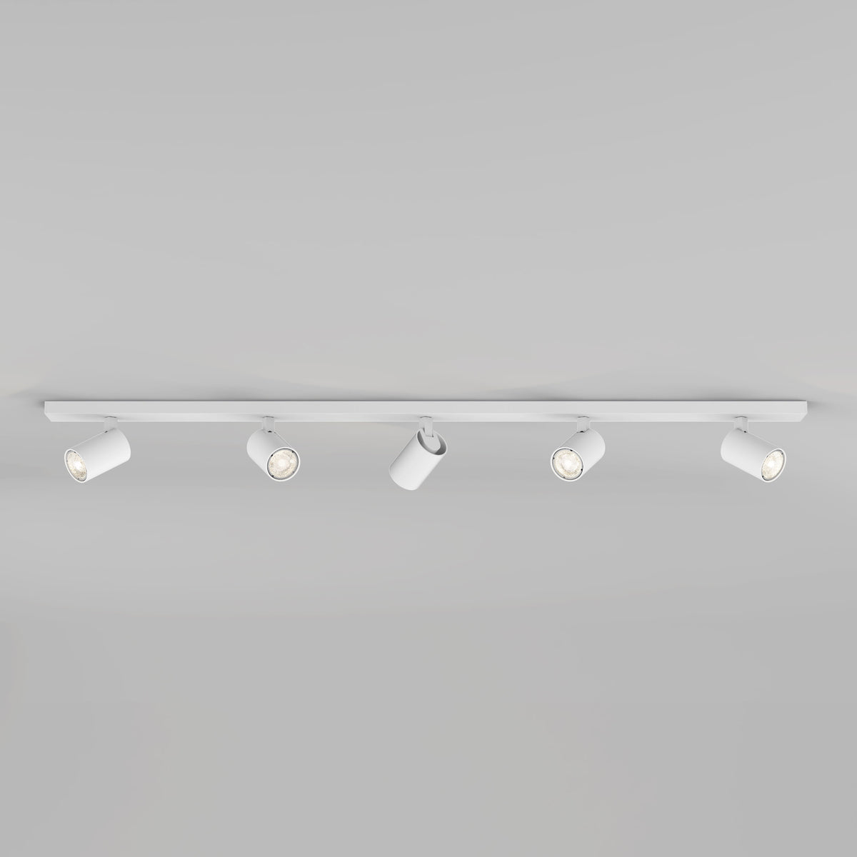White track lighting fixture with five adjustable spotlights on a light grey background