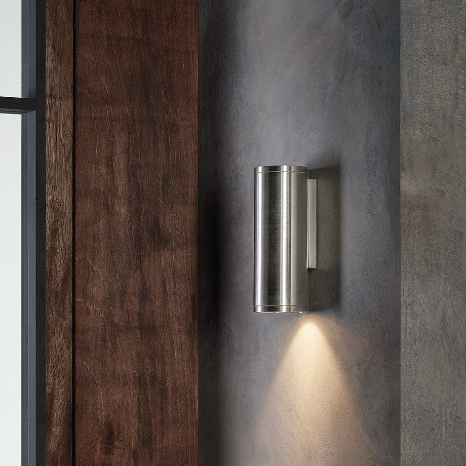 Brushed steel cylindrical outdoor wall light with light shining downwards
