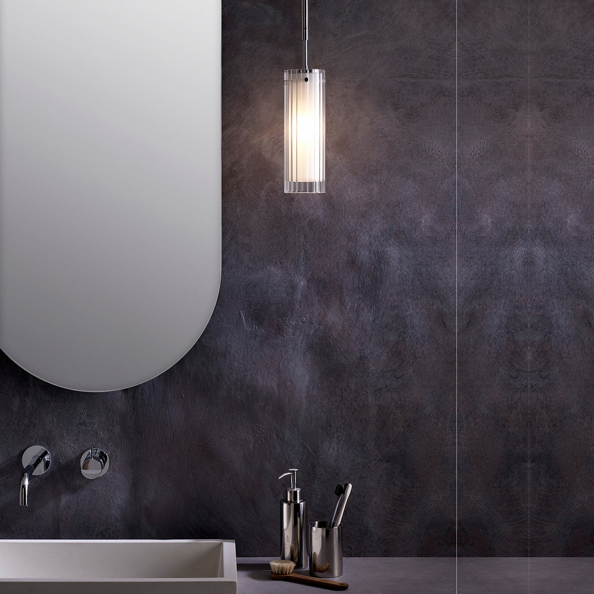 Modern bathroom with dark textured walls, oval mirror, white sink, and chrome fixtures