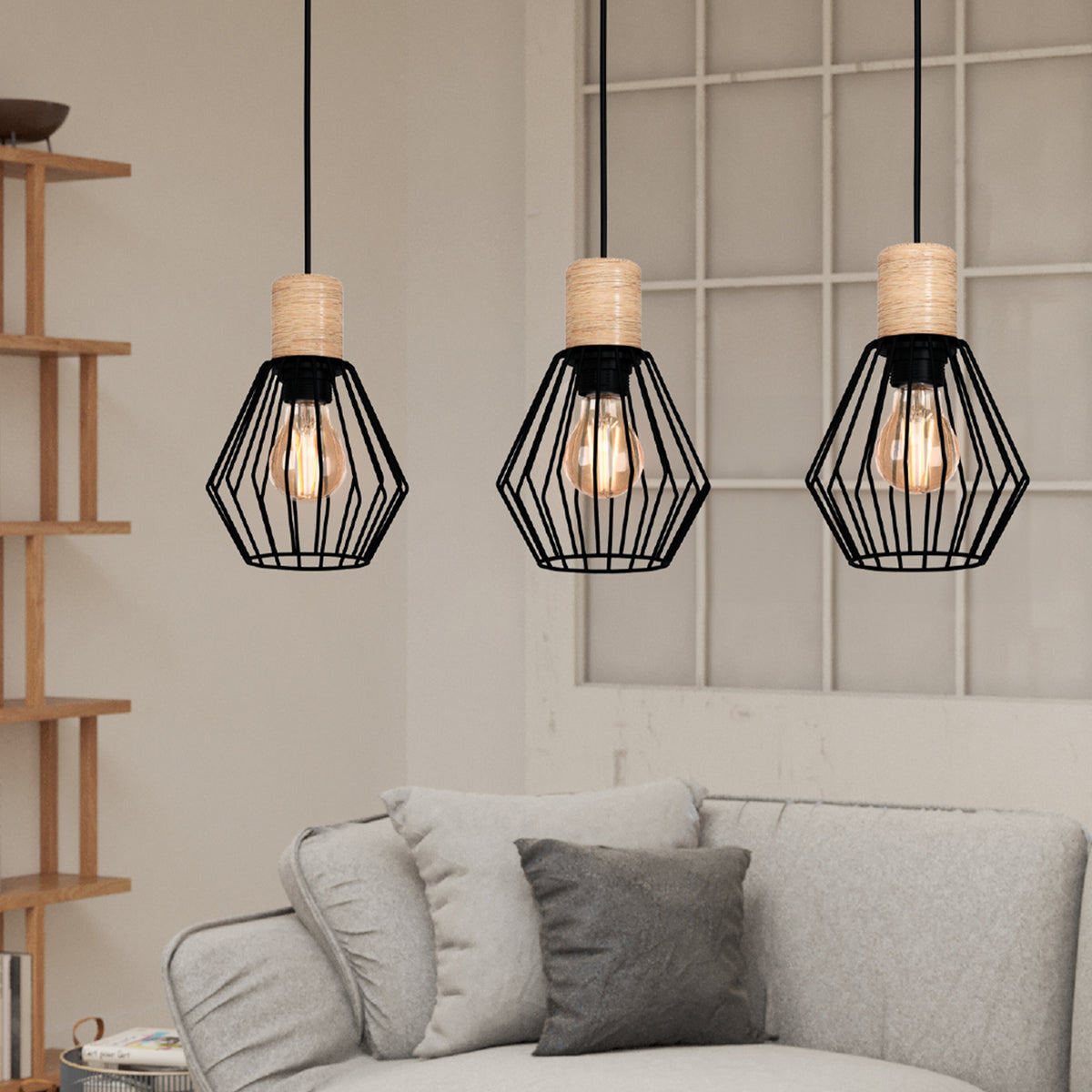 Three pendant lights with black geometric cages and wood accents hang above a light gray sofa with pillows