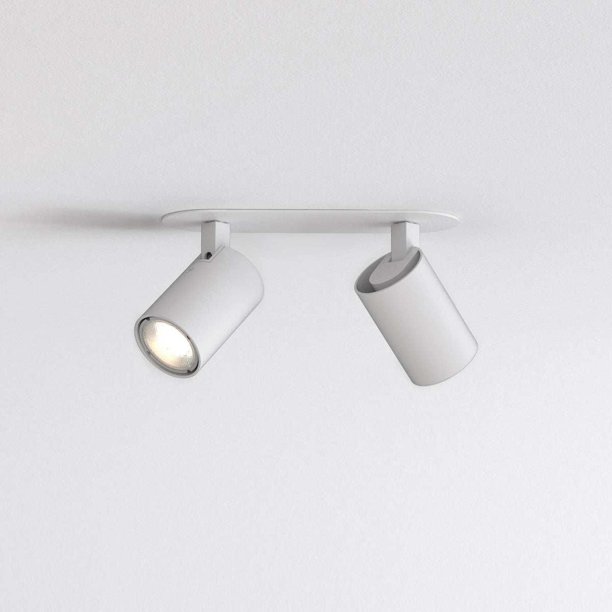 Two white ceiling-mounted spotlights, one illuminated, against a white textured ceiling and wall