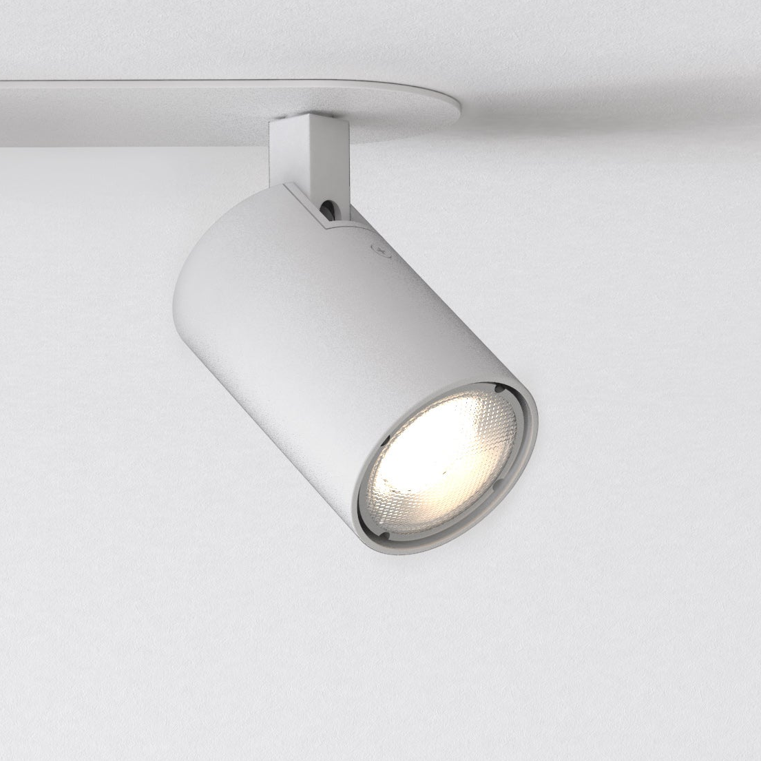White cylindrical ceiling spotlight with a bright bulb, mounted on a white track