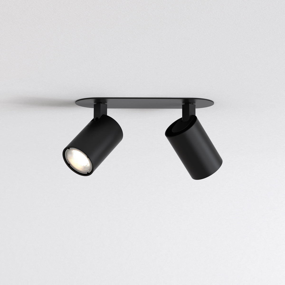 Two black cylindrical ceiling spotlights on a black rectangular base, one light is on