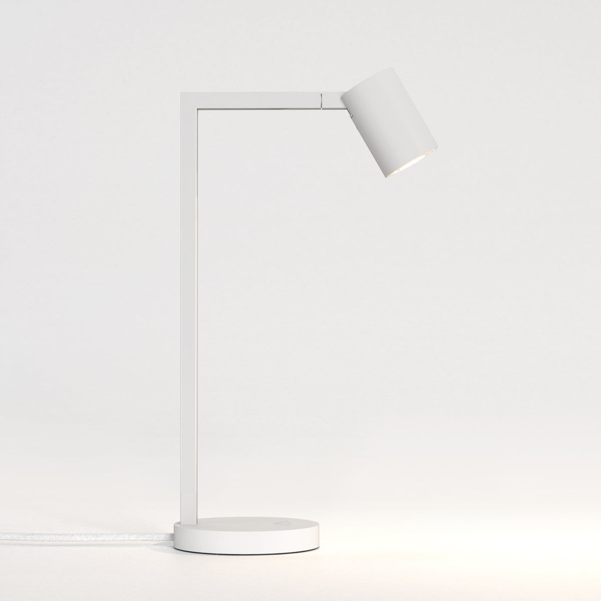 White desk lamp with a rectangular arm and a cylindrical head, emitting a warm light downwards