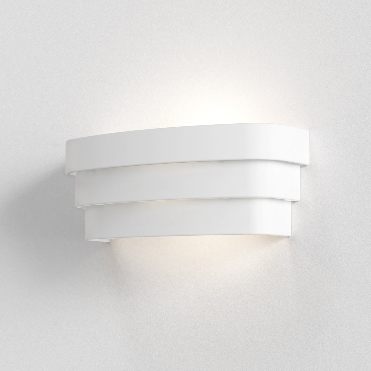 White wall light with three curved horizontal bands, emitting light upwards and downwards onto a white wall