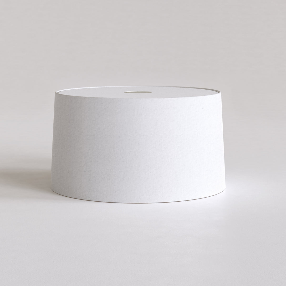 White cylindrical lampshade with a small circular opening at the top