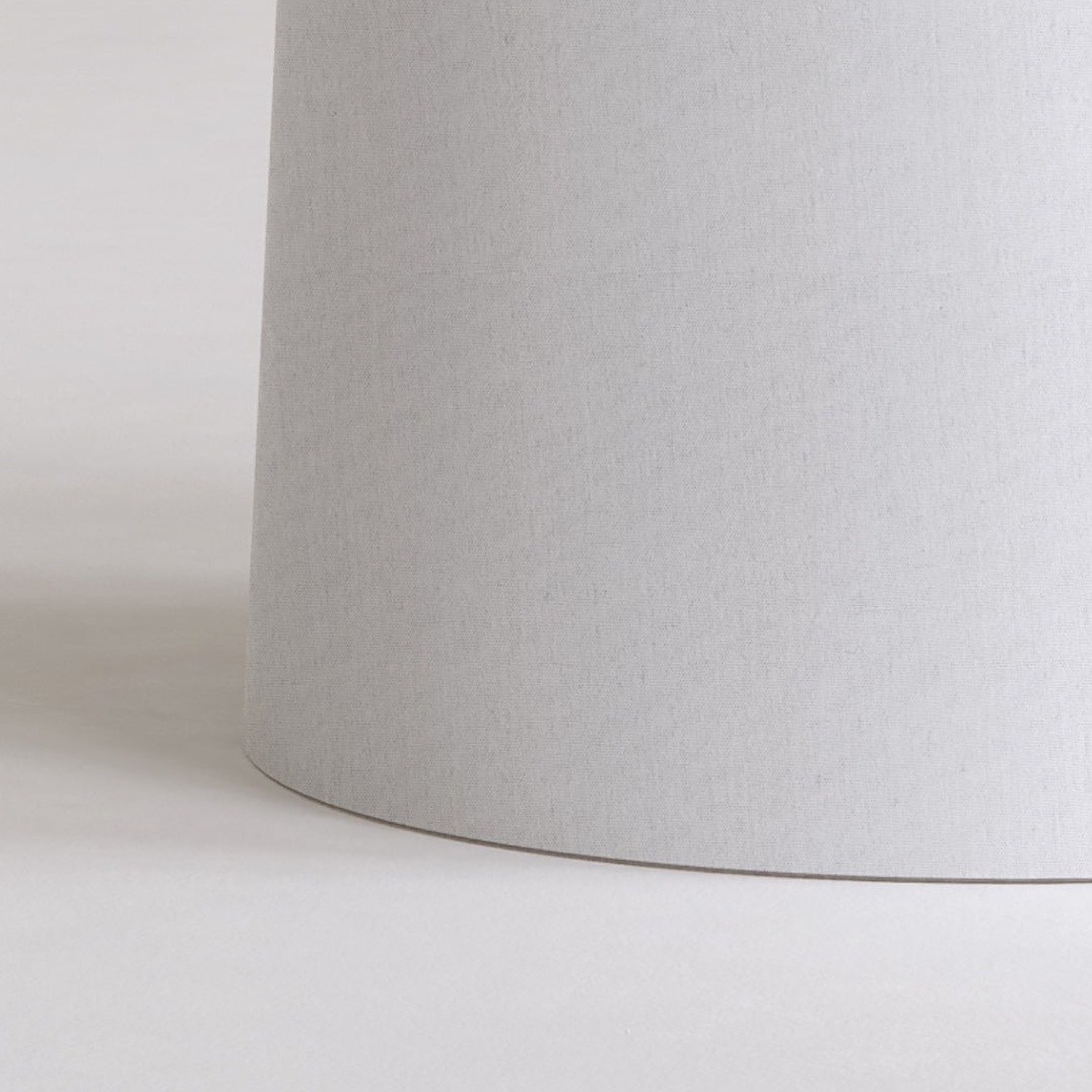 Close up of a light grey cylindrical lampshade on a white surface