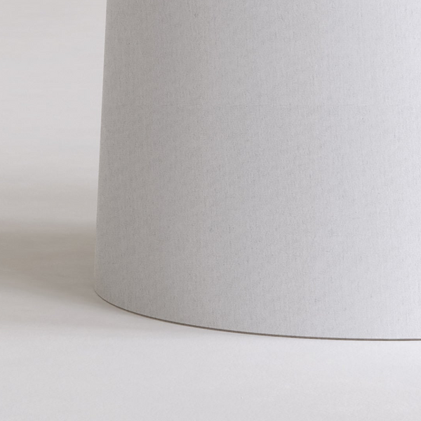 Close up of a light grey cylindrical lampshade on a white surface