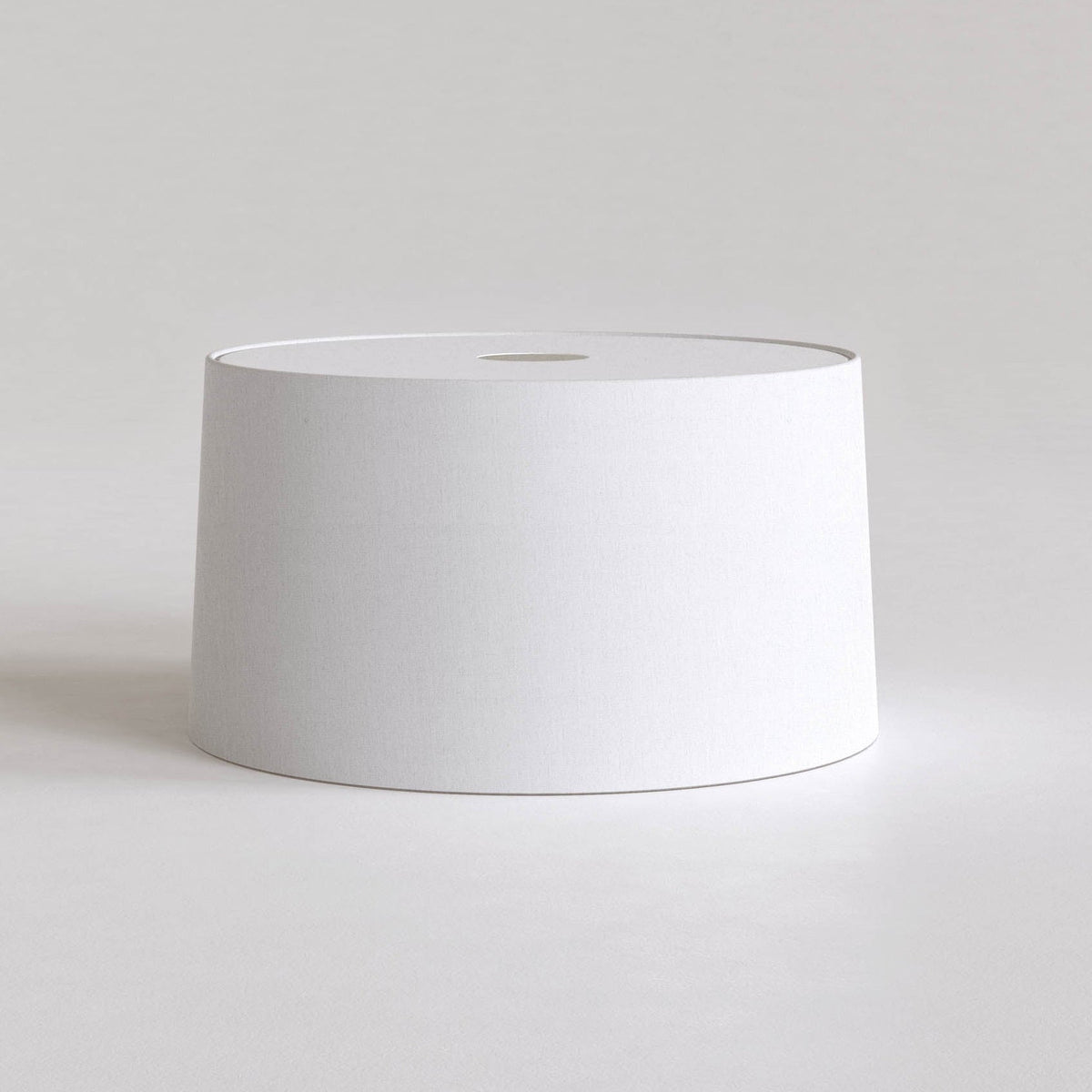 White cylindrical lampshade with a small circular opening at the top