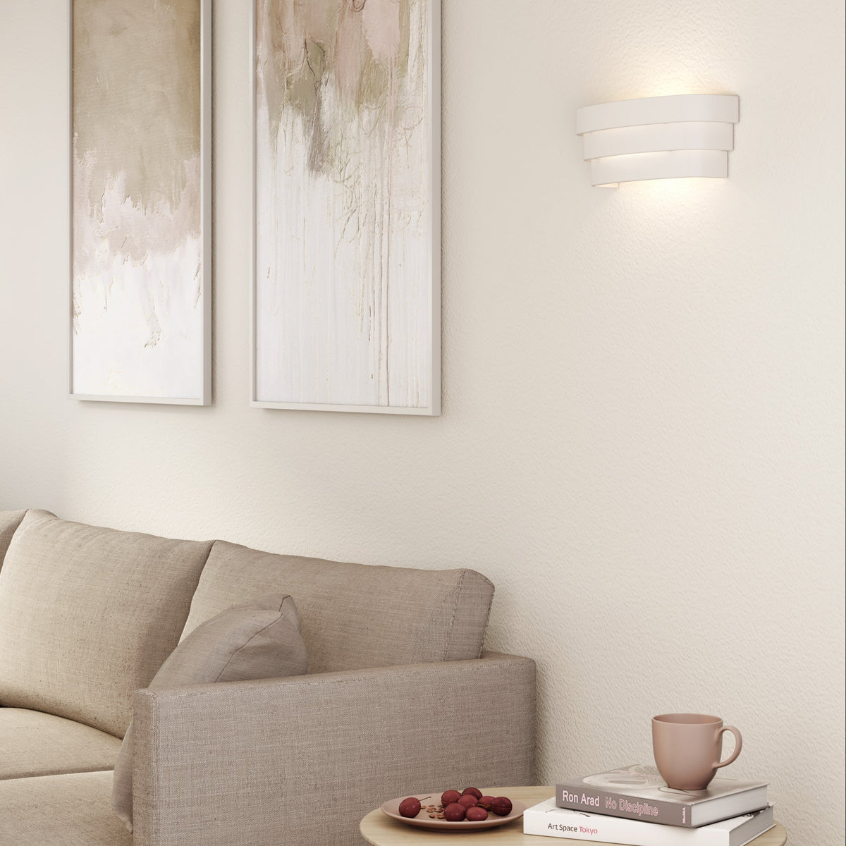 A beige sofa with two abstract paintings on the wall and a modern white wall light