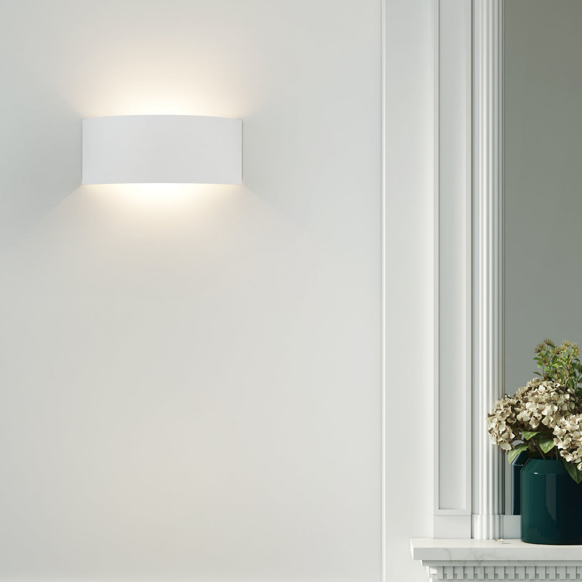 White wall sconce light fixture illuminates a white wall above a marble mantelpiece with a green vase