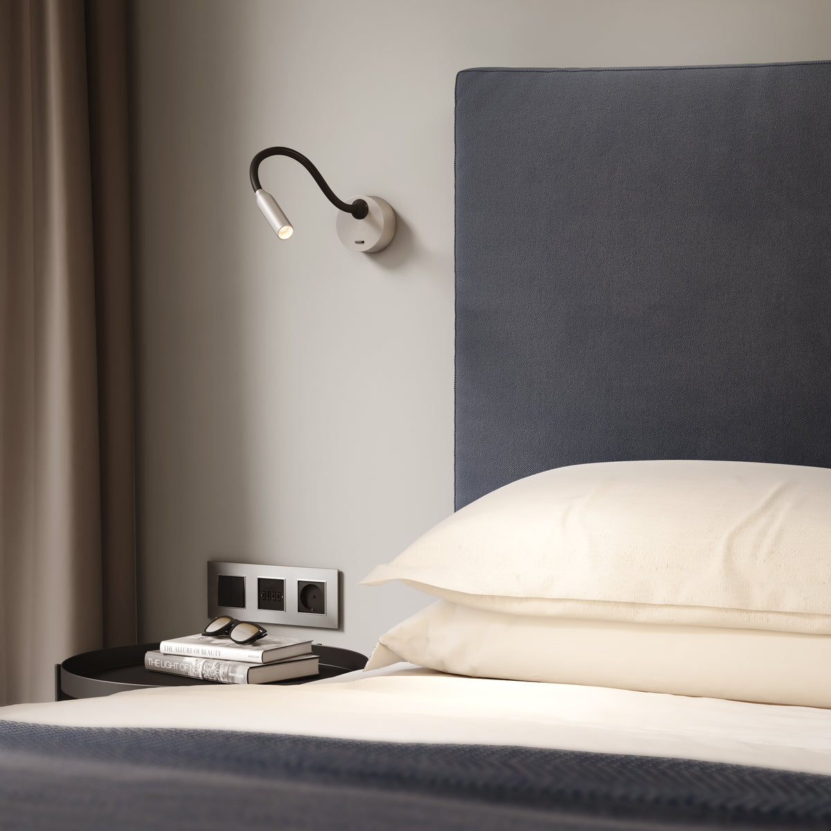 Astro Lucca Surface Switched LED Reading Light in Matt Nickel above a bed with books and sunglasses