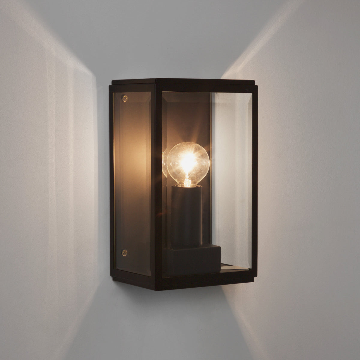 Black rectangular wall light with clear glass panels and a visible glowing bulb inside