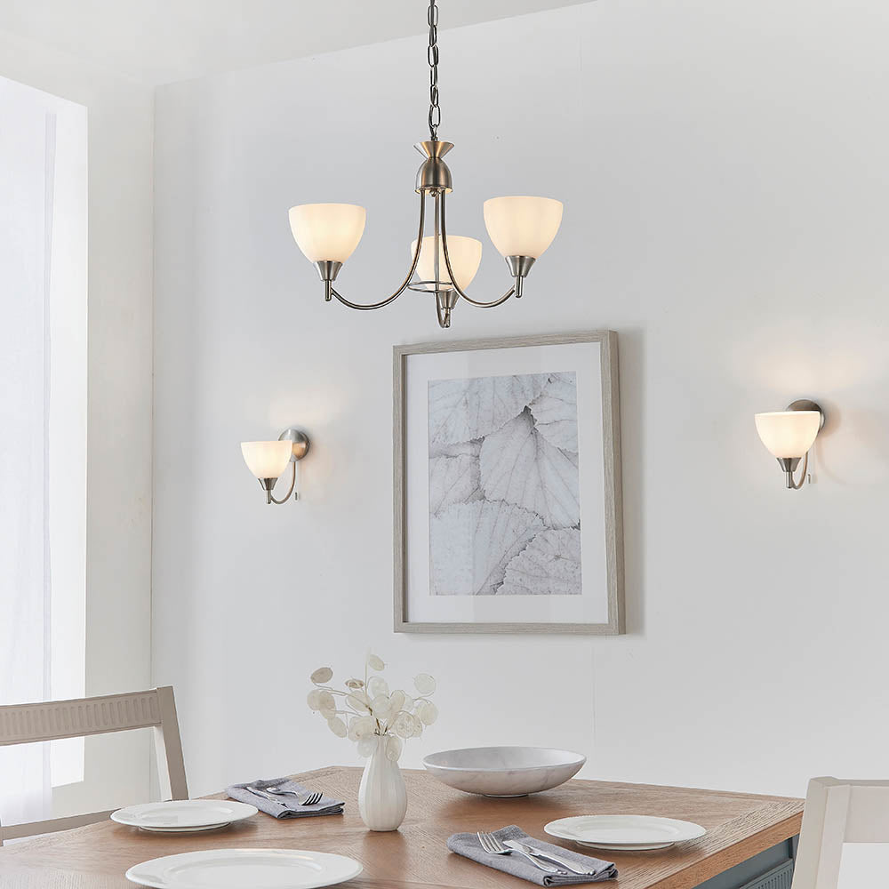 Dining room with a three-light chandelier and two matching wall lights, all with opaque white glass shades.