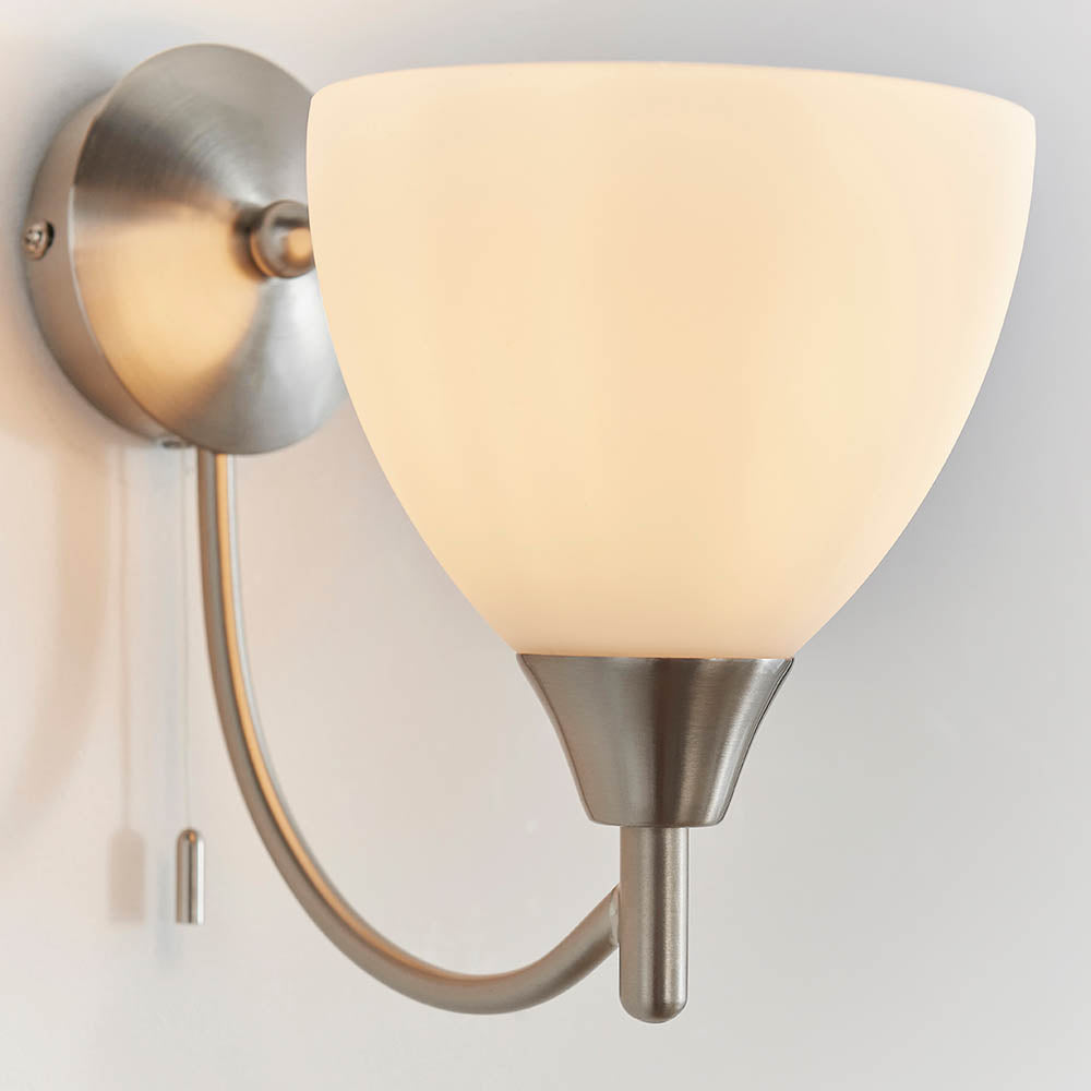 Brushed chrome wall light with a curved arm and an opaque white glass shade.
