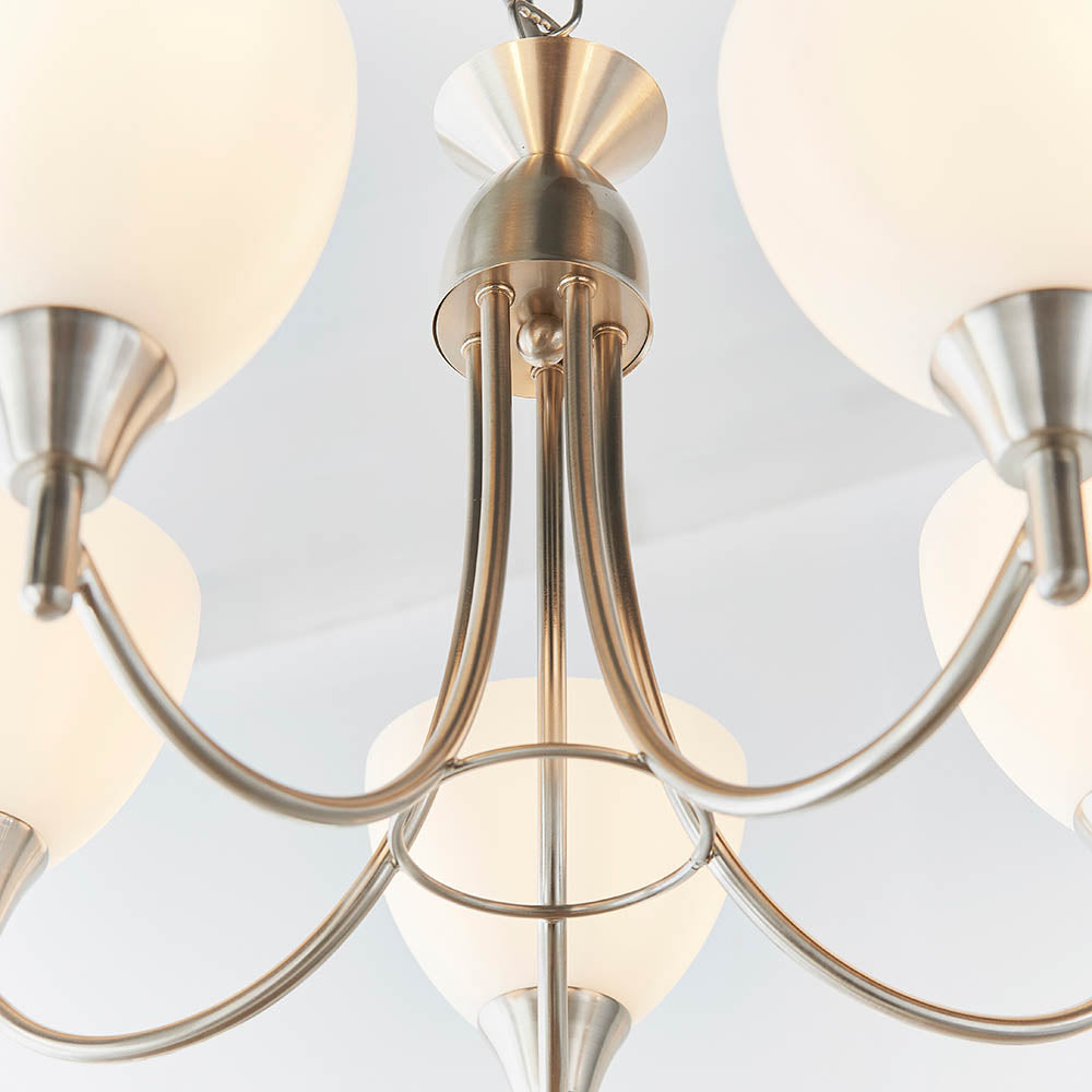 Close-up of the central column and arms of a five-arm chandelier with a brushed chrome finish.
