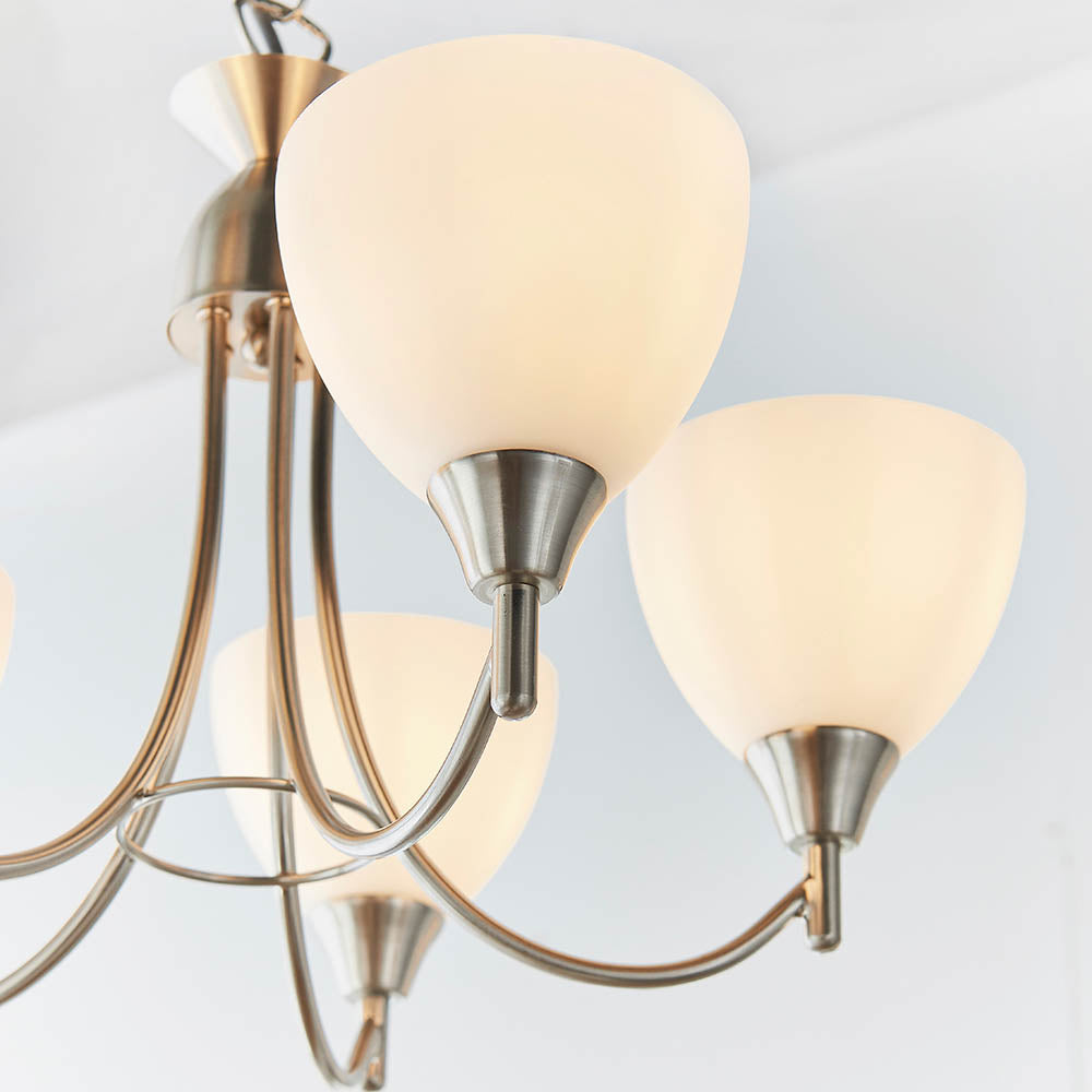 Close-up of two white glass shades and the brushed chrome arms of a chandelier.