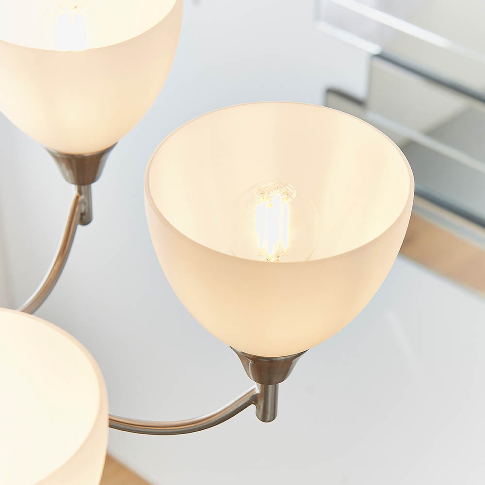 Close-up of a single white glass shade on a chandelier, revealing the light bulb inside.