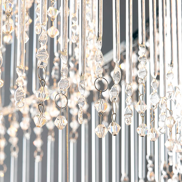 Detailed view of clear crystal beads and rods hanging from a chandelier, with soft light reflecting.