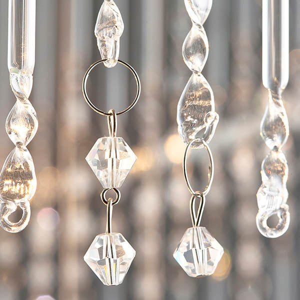Close-up of individual crystal strands on a chandelier, featuring clear faceted beads and twisted glass elements.