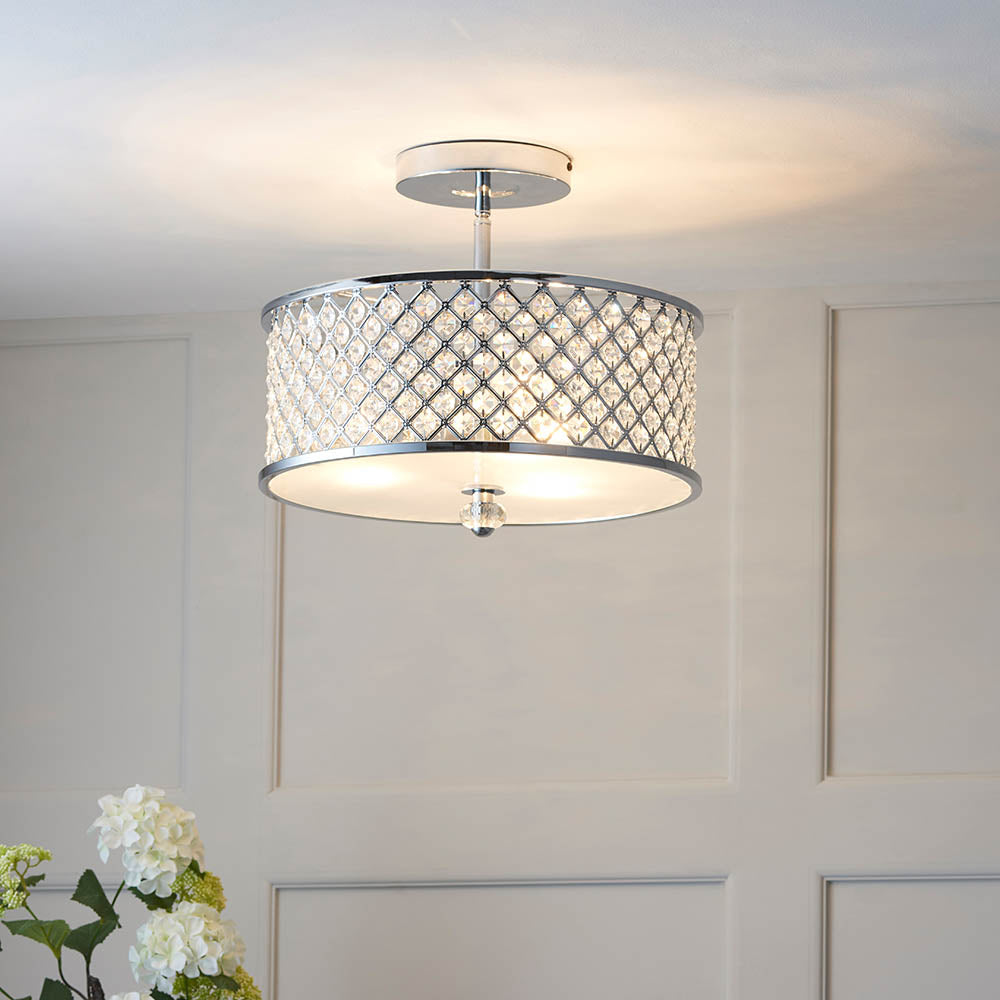 A chrome and crystal semi-flush ceiling light illuminates a white room with decorative wall paneling.