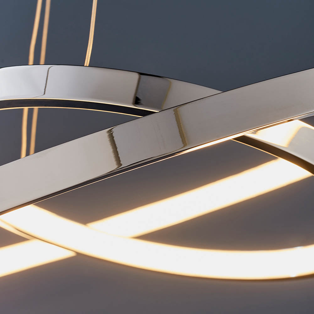 Close-up of the polished chrome and illuminated LED strips of a modern pendant light.